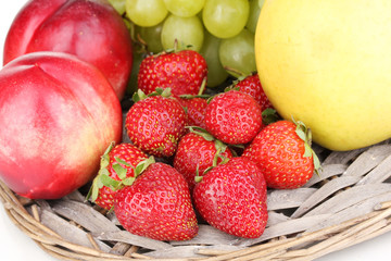 ripe sweet fruits and berries on wicker mat close-up