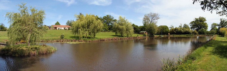 Fototapeta na wymiar Panorama of a rural property with a house and a pond, France