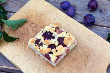 Plum cake and fresh plums on wooden table