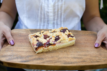 Obraz na płótnie Canvas Prune fruit cake on wooden plate with hands
