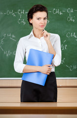 Serious teacher is near the school blackboard