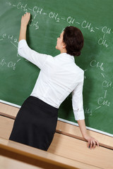 Teacher writes formulas with chalk at the blackboard