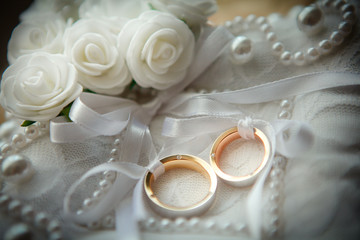 Two wedding rings with white flower in the background.