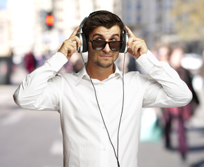 portrait of young man listening to music using headphones at cro