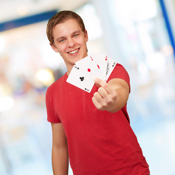 Portrait of a young man holding ace cards