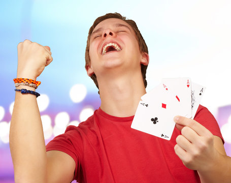 portrait of young man doing a winner gesture playing poker over