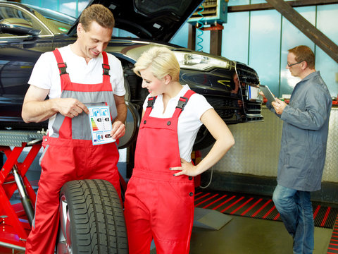 Master mechanic explaining  tyre labeling to a trainee in a gara