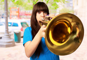 portrait of a young girl blowing trumpet