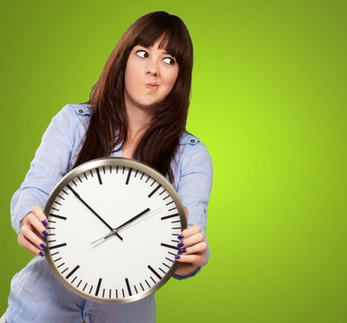 A Young Girl Holding A Clock And Making Face