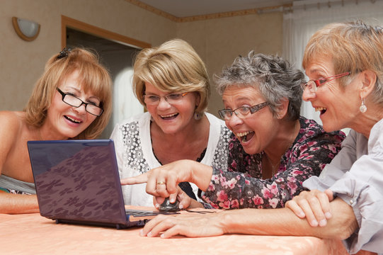 Senior - femmes joyeuses utilisant un ordinateur en groupe