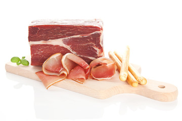 Prosciutto on wooden cutting board.