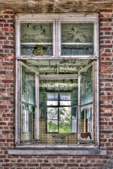 Fototapeta na wymiar Rozbite okna w czerwonej cegły ściany w opuszczonej stacji kolejowej