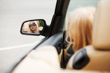 Young woman looking in the car mirror