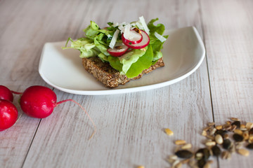 Healthy sandwich with salad, radish and pumpkin seeds