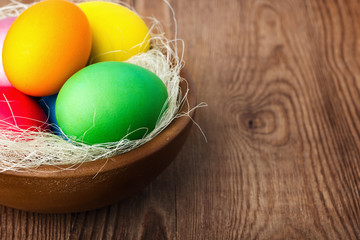 easter basket with easter eggs on wooden background