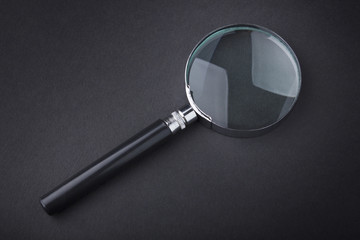 Closeup of magnifying glass on dark surface