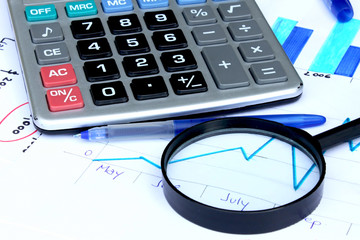 magnifying glass over financial chart,pen,calculator