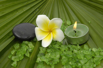 frangipanis and candle with zen stones with green bath salts