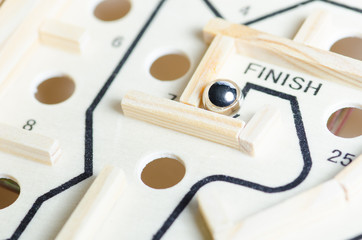 A closeup of a ball on wooden maze at Finish