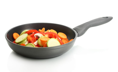 frying pan with vegetables on white