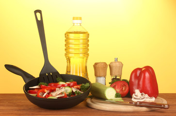 frying pan with vegetables on yellow background