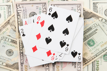 Fototapeta na wymiar Dollars and a deck of playing cards on black background