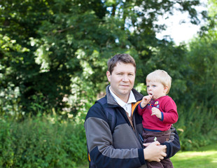 Young father and toddler walking through nature park