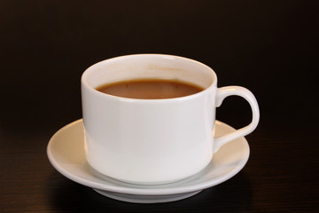 Cup of coffee on wooden table on brown background