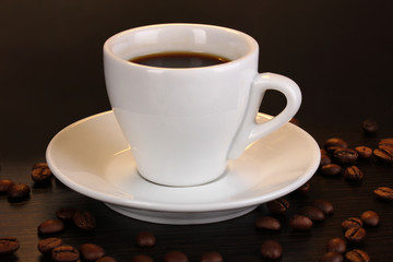 Cup of coffee on wooden table on brown background