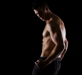 Fototapeta na wymiar Strong muscular athlete posing on black