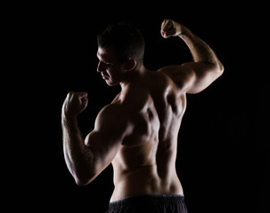 Fototapeta na wymiar Strong sports man showing muscular back on black
