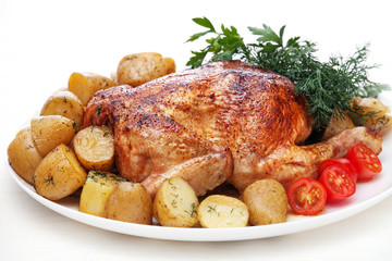 Whole roasted chicken with potatoes and herbs on white backgroun