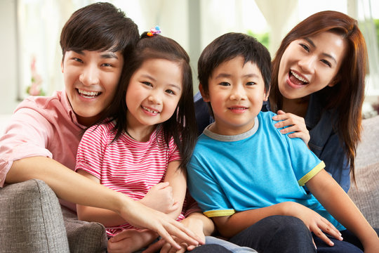 Chinese Family Relaxing On Sofa At Home