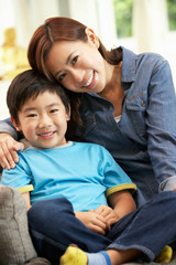 Fototapeta premium Chinese Mother And Son Sitting On Sofa At Home Together
