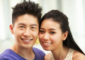 Young Chinese Couple Relaxing On Sofa At Home