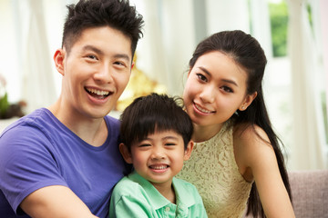 Chinese Family Sitting And Relaxing On Sofa Together At Home