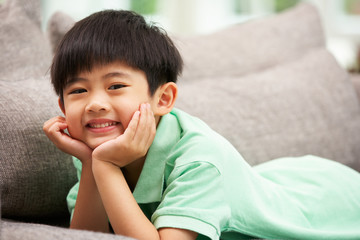 Young Chinese Boy Relaxing On Sofa At Home