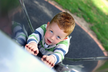 little boy slding down the slide at the park