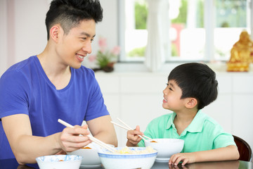 Chinese Father And Son Sitting At Home Eating A Meal