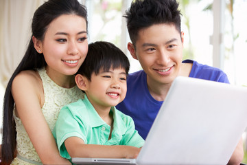 Chinese Family Sitting At Desk Using Laptop At Home