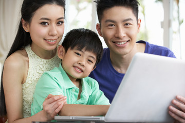 Chinese Family Sitting At Desk Using Laptop At Home