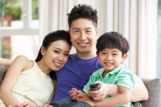 Chinese Family Sitting And Watching TV On Sofa Together