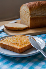 slice of buttered toast in front of loaf of bread