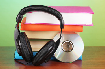 Headphones on books on wooden table on turquoise background