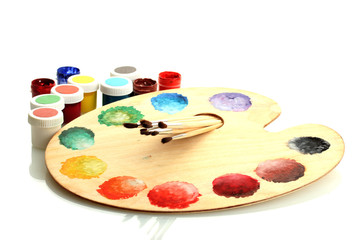 wooden art palette with paint and brushes isolated on white
