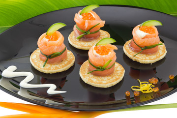 Red salmon roll with cheese, caviar and cucumber on” blinis”