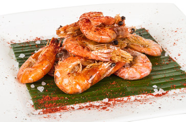 fried black tiger prawns with herbs and spices on banana leaf