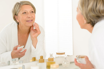 Senior woman look at herself bathroom mirror reflection