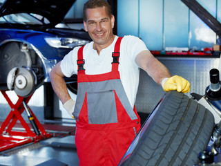 Master mechanic with summer tyre is proud of good service