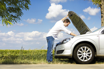 Man fixing a broken car by the road